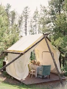 a tent set up in the woods with tables and chairs