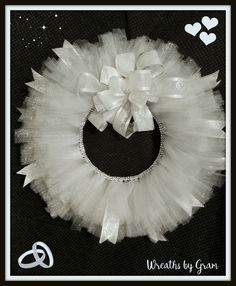 a white tutu skirt with a bow on the front and side, attached to a black background