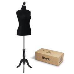 a black mannequin on a stand next to a cardboard box