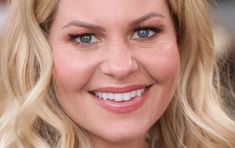 a close up of a woman with blonde hair and blue eyes smiling at the camera