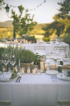 the table is set with candles and greenery for an outdoor dinner party or celebration