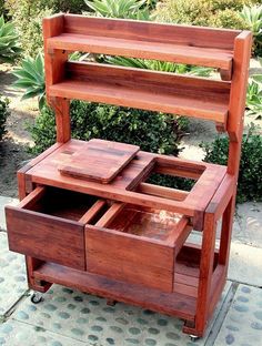 a wooden cart with drawers on wheels is shown in front of some plants and bushes