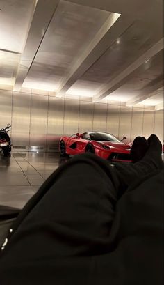 two red sports cars parked in a parking garage next to a person's feet