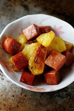 a white bowl filled with sliced pineapple and other fruit on top of a table