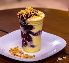 a dessert in a plastic cup on a plate with granola and yogurt