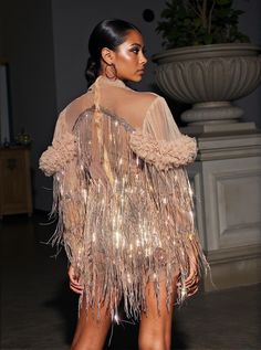 a model walks down the runway in a sheer dress with fringes and beads on it