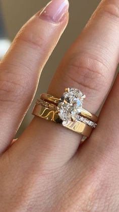 a woman's hand with two gold rings on it and one diamond in the middle