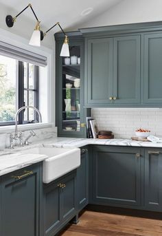 a kitchen with blue cabinets and marble counter tops, along with a white sink in the center