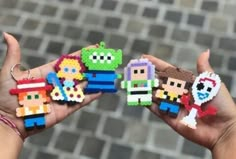 two hands are holding some pixelated toys