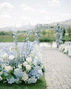 blue and white flowers on the ground in front of an arch at a wedding ceremony