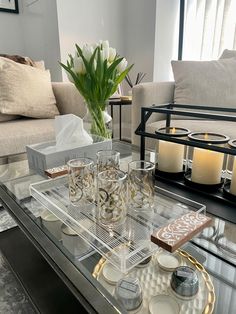 a glass coffee table with candles and plates on it