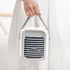 a woman holding a white portable air conditioner