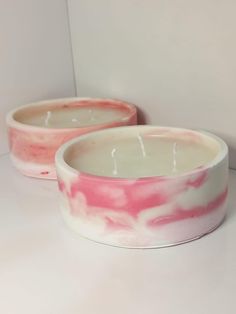 two pink and white bowls sitting next to each other on top of a countertop