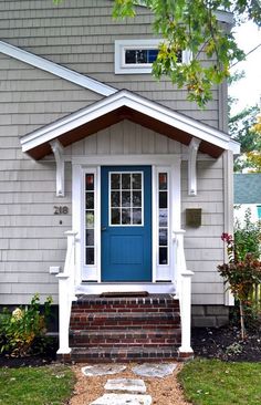 a blue front door on a house with steps leading up to the porch and side entrance