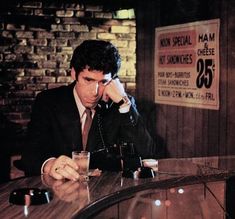 a man sitting at a table in front of a glass talking on a cell phone