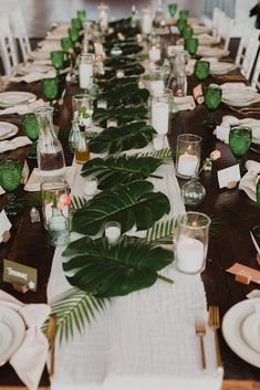 a long table is set with place settings and greenery for dinner guests to enjoy