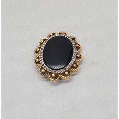 Circa 1980s goldtone oval smooth faux-onyx center with tiny round clear rhinestones surround brooch with security clasp and loop to be worn as a pendant. Measures: 1 3/8 inches long by 1 1/8 inches wide. Condition: Very good; a few of the tiny clear rhinestones have darkened, but they're so small it's not very noticeable. Gold Oval Brooch For Evening, Elegant Oval Cabochon Brooch Jewelry, Formal Round Costume Jewelry Brooches, Oval Costume Jewelry Brooch, Oval Brooches For Evening, Oval Evening Brooches, Gold Brooches, Pearl Brooch, Georg Jensen