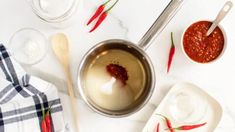 some chili sauce and other condiments on a white counter top with spoons