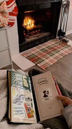 a person sitting in front of a fire place holding a book and writing on it