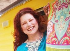 a woman is smiling and holding onto a colorful cloth