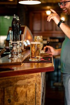 a man standing at a bar with a glass of beer