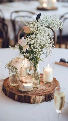 flowers and candles are placed in mason jars on a wood slice at a wedding reception