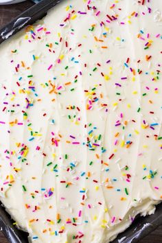 a cake with white frosting and colorful sprinkles on it in a pan