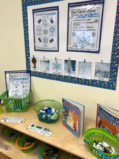 several books and baskets on a table in front of a bulletin board with pictures above them