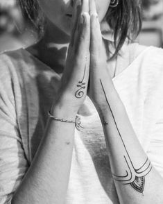 black and white photograph of woman with two tattoos on her arms, both holding their hands together