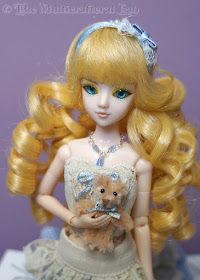 a doll with blonde hair holding a teddy bear