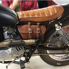 a close up of a motorcycle with a brown leather saddlebag on the back seat