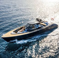 a black and tan motor boat in the middle of the ocean with people on it