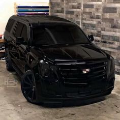 a black suv parked in front of a brick wall