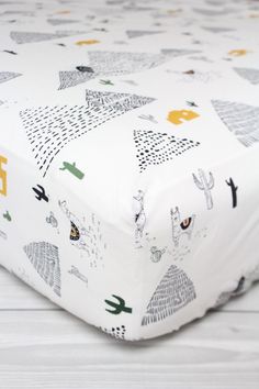 a close up of a baby crib sheet with animals on it and trees in the background