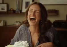 a woman sitting at a table with a cake in front of her and smiling for the camera