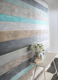 a vase with flowers sitting on top of a table next to a wall made out of wood planks