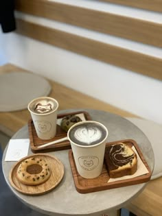 two cups of coffee and some pastries on a table with stairs in the background