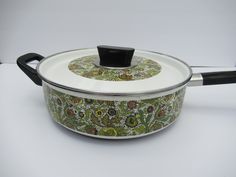 a pot with a lid and handle sitting on a table