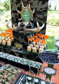 an assortment of desserts and snacks are displayed on a table in front of a camouflage backdrop