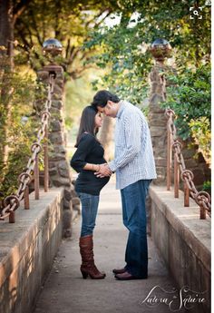 a man and woman kissing on a bridge