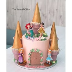 a pink cake with princess figurines and decorations on it's top, sitting on a table