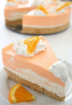 a slice of orange cheesecake on a white plate with an orange slice next to it