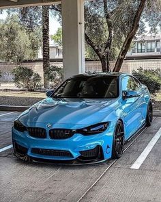 a blue bmw car parked in a parking lot next to some trees and building with palm trees