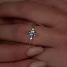 a woman's hand holding a ring with a blue topazte and diamond