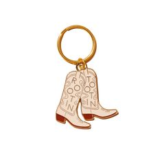 a gold keychain with a pair of boots on the bottom and words written in white