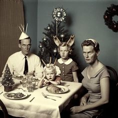 an old black and white photo of a family sitting at a table for christmas dinner