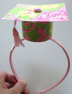 a person is holding a pink and green paper hat with tassels on it