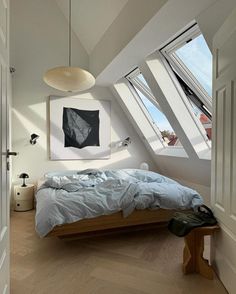 a bed sitting under two windows in a bedroom next to a wooden floor and white walls