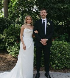 a man and woman in formal wear standing next to each other on a brick walkway