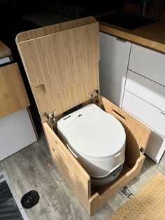 a white toilet sitting inside of a wooden box on the floor next to a counter